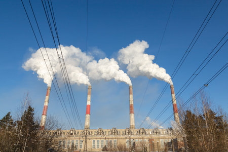 The chimneys of thermal power plants spew smoke into the air against the blue winter sky. CHPP-10 is...