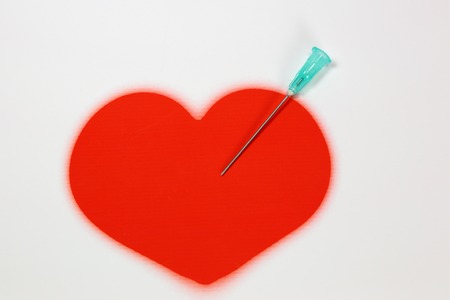 Needle with a red heart on a white backgroundの写真素材