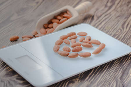 nuts almonds on scales and wooden backgroundの写真素材