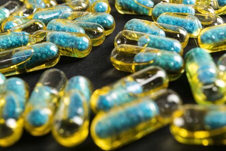 Gelatin capsules with the drug scattered from the bottle on the table.の写真素材