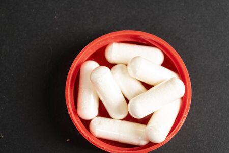 Gelatin capsules with the drug scattered from the bottle on the table.の写真素材