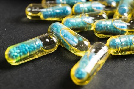 Gelatin capsules with the drug scattered from the bottle on the table.の写真素材