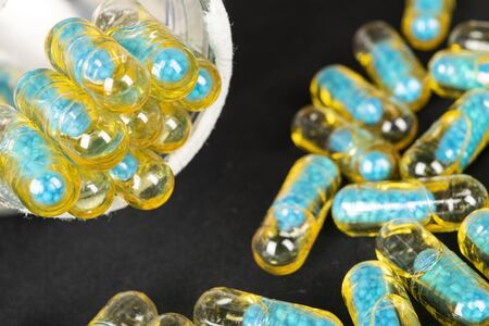 Gelatin capsules with the drug scattered from the bottle on the table.の写真素材