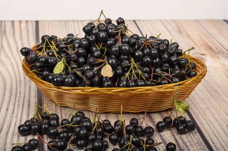 Ripe Aronia berries in a wicker basket on the table.の写真素材