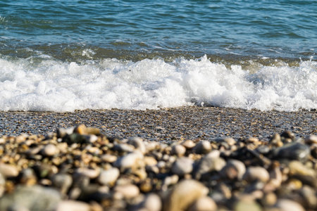 Sea wave on a pebble beach, foreground out of focus