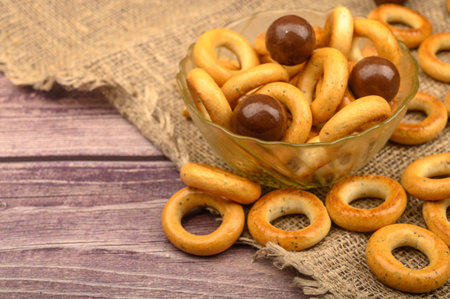 Small bagels, brown sugar and ceramic dishes on a wooden background close-up