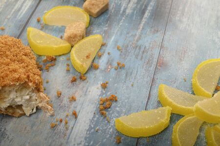 One broken cake, pieces of brown sugar and marmalade lemon slices on a wooden backgroundの写真素材