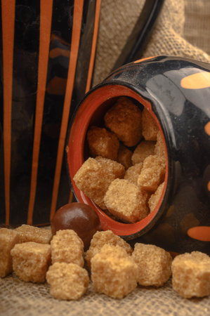 Pieces of brown sugar, a sugar bowl, and pottery against a background of coarse homespun cloth. Close upの写真素材
