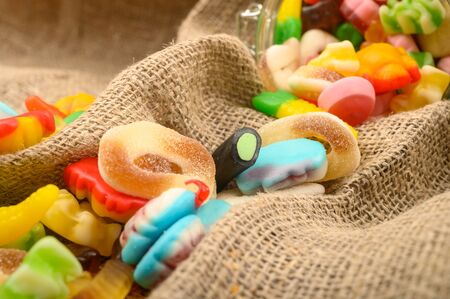 Multicolored shaped marmalade on a background of rough homespun fabric close-up. Delicious holiday treatの写真素材