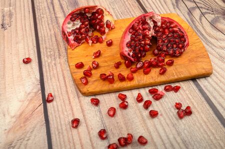 Pieces of ripe juicy pomegranate and pomegranate seeds on a wooden Board on a wooden background. Close upの写真素材