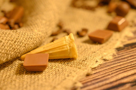 Cake in a waffle cone, chocolate and coffee beans on a background of rough homespun fabric. Close upの写真素材
