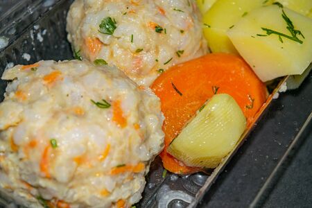 meat meatballs with boiled potatoes and boiled carrots in a plastic container on a dark background. Close upの写真素材