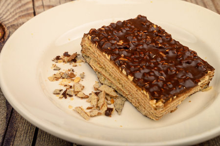 A piece of waffle cake on a white plate on a wooden background. Close up
