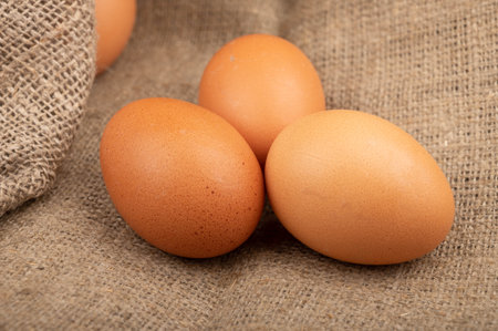 Chicken eggs on a background of rough homespun fabric. Homemade preparations, rustic treats. Close...