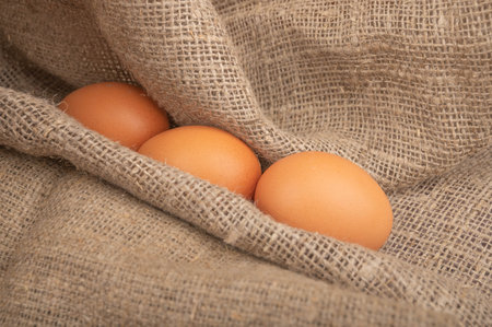 Chicken eggs on a background of rough homespun fabric. Homemade preparations, rustic treats. Close...