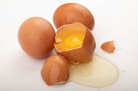 A broken chicken egg and several eggs on a white background. Country food. Close up
