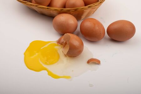 A broken chicken egg and scattered eggs on a white background. Close upの写真素材