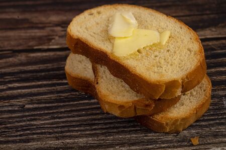Fresh wheat toast with butter on a wooden background. Close upの写真素材