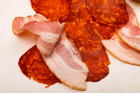 Slices of bacon and sausage on a white background. Close up