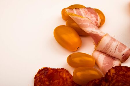 Slices of bacon and sausage and tomatoes on a white background. Close upの写真素材