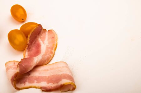 Bacon slices and tomatoes on a white background. Close upの写真素材