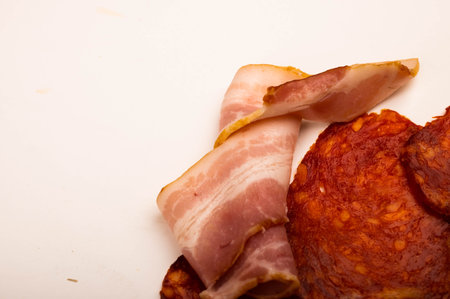 Slices of bacon and sausage on a white background. Close up