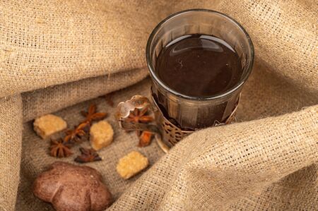 A faceted glass of tea in a vintage Cup holder, bagels, cookies and chocolate gingerbread on a background of rough homespun fabric. Close upの写真素材