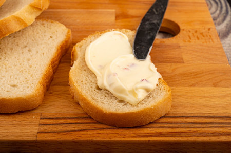 A sliced loaf of wheat bread and a sandwich with melted cheese on a wooden cutting Board. Close up.