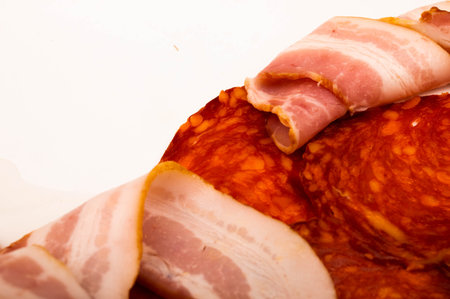Slices of sausage and bacon on a white background. Close up