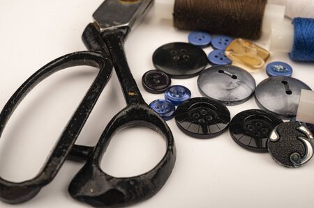 Several multi-colored buttons of different sizes and large vintage sartorial scissors on a white background. Close upの写真素材