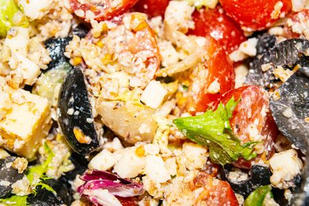 Vegetable salad with cheese. Fitness salad with tomatoes, onions, olives, lettuce and cheese. Surface texture. Close upの写真素材