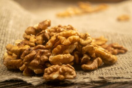 Peeled walnuts in bulk on a wooden table covered with rough-textured burlap. Healthy diet. Fitness diet. Close upの写真素材