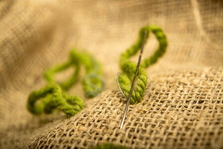 Stitches of green thread on the burlap with a rough texture. Close upの写真素材