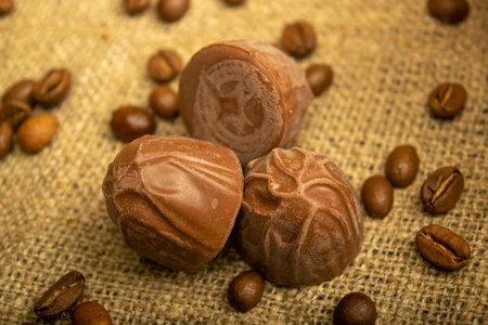 Chocolate, coffee beans and chunks of brown cane sugar on a background of homespun fabric with a...