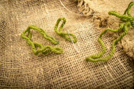 Stitches of green thread on the burlap with a rough texture. Close up