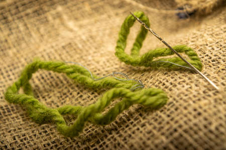 Stitches of green thread on the burlap with a rough texture. Close upの写真素材