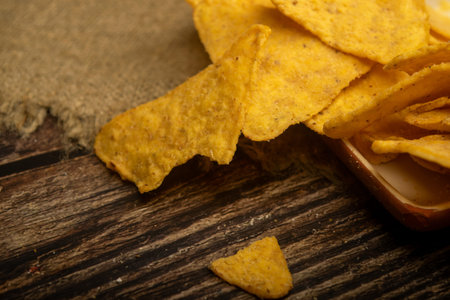 Corn chips with cheese sauce and a coffee mug on a wooden background. Close up