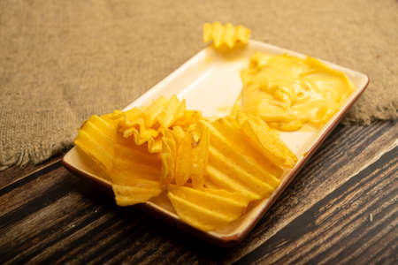 Potato chips with cheese sauce on a wooden background. Close upの写真素材