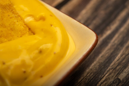 Corn chips with cheese sauce on a wooden background. Close up