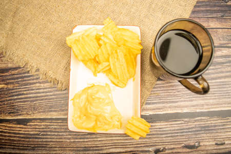 Corn chips with cheese sauce and a coffee mug on a wooden background. Close upの写真素材
