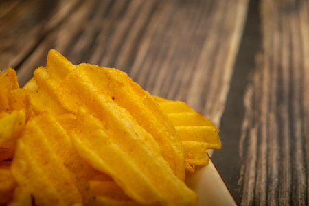 Potato chips with cheese sauce on a wooden background. Close up