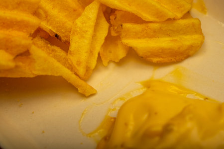 Potato chips with cheese sauce on a wooden background. Close up
