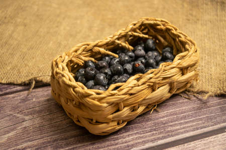 Blueberry in a wicker basket on a background of homespun fabric with a rough texture. Close upの写真素材