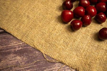 Ripe juicy cherries scattered on a homespun fabric with a rough texture. Close upの写真素材
