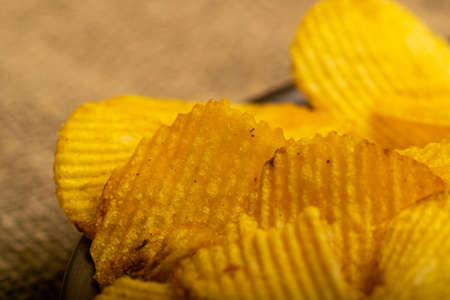 Fluted potato chips on a background of homespun fabric with a rough texture. Close upの写真素材