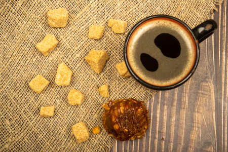 A mug of coffee, pieces of brown cane sugar, and a cake on the wooden table. Close upの写真素材