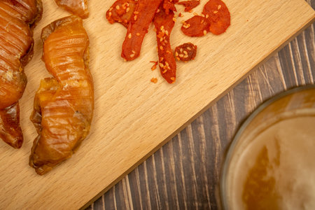 Dried halibut caviar and dried crab meat on a wooden serving Board and a mug of beer on a wooden...