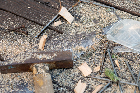 Old vintage hammer, wood saw, nails, safety glasses and sawdust on a wooden background, close-up,...