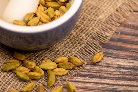 Cardamom in a ceramic mortar and cardamom in a loose background of coarse burlap, close-up,...