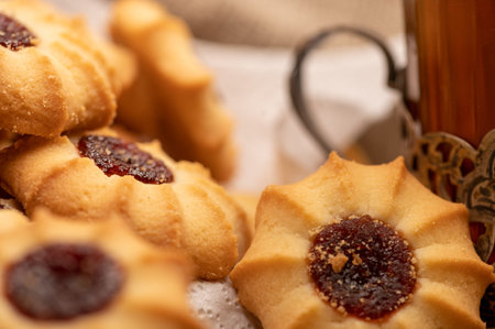Homemade pastry cookies with jam and a faceted glass of tea in a vintage Cup holder on a background...
